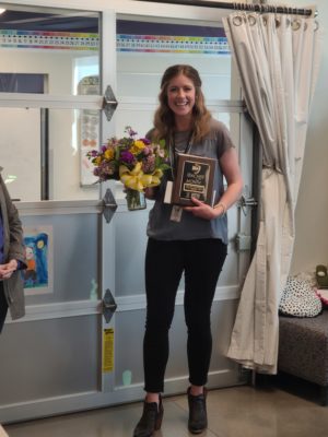 Photo of Kaci Hauptman, 2nd-Grade Teacher at Bryant Elementary, holding a bouquet of flowers and plaque after KMTX Teacher of the Month for March award