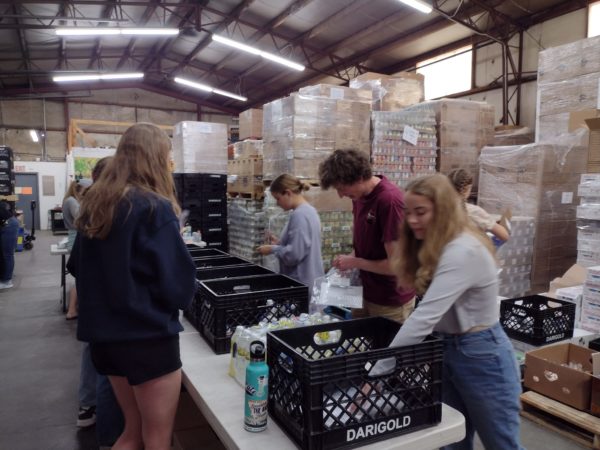 Helena High School Science Seminar and AP Environmental Studies students work around a table to assemble emergency food packs at Montana Food Share